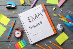 Inscription Exam, Results and stationary on wooden background, top view
