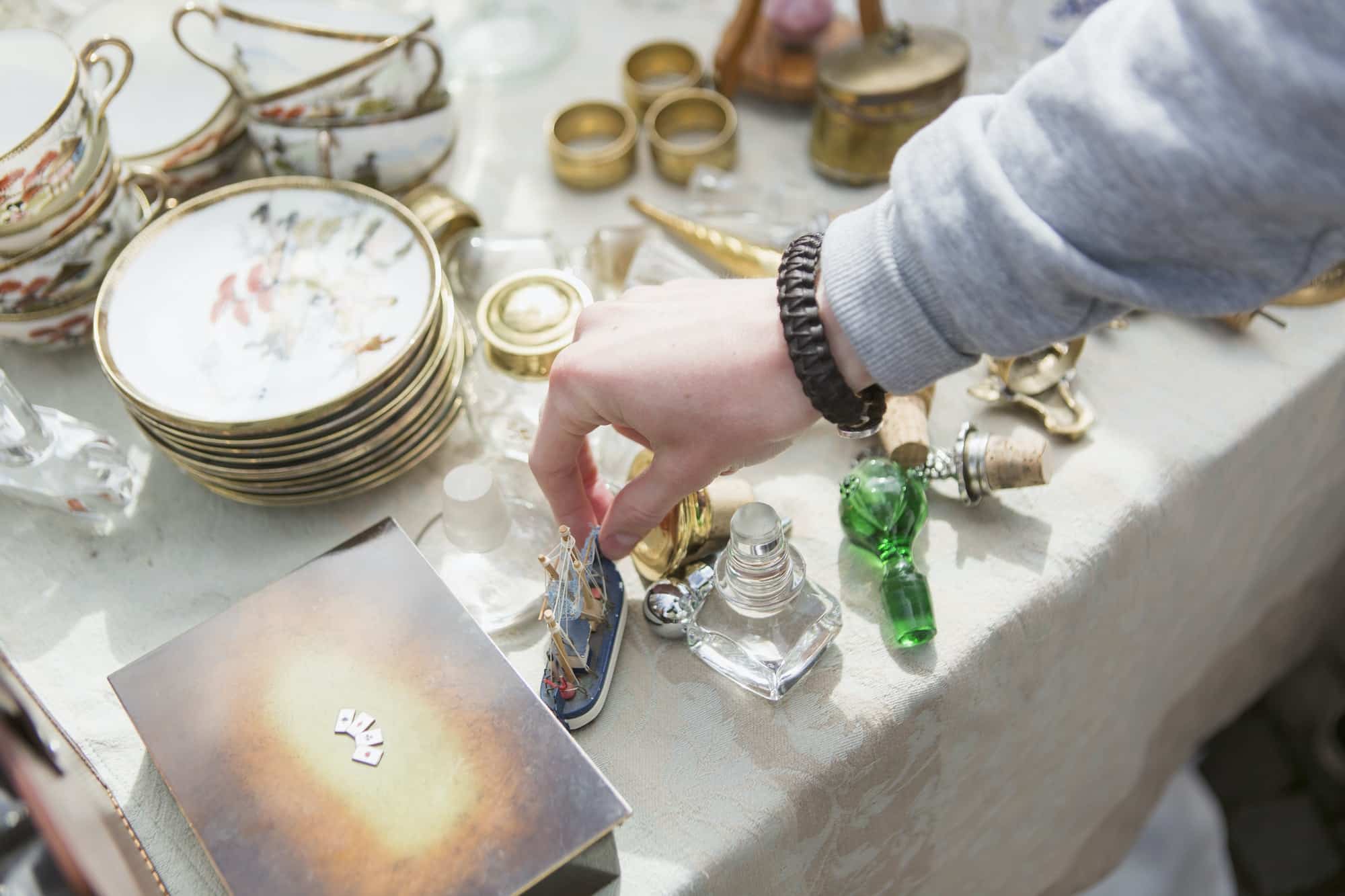 Cropped hand of man holding antique ship toy on table at flea market