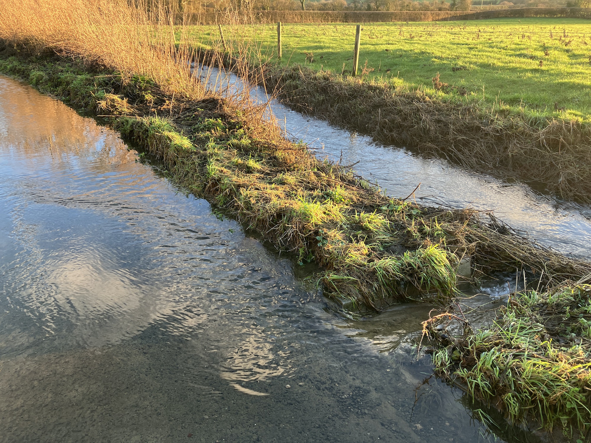 Flooded rural lane and stream in winter
