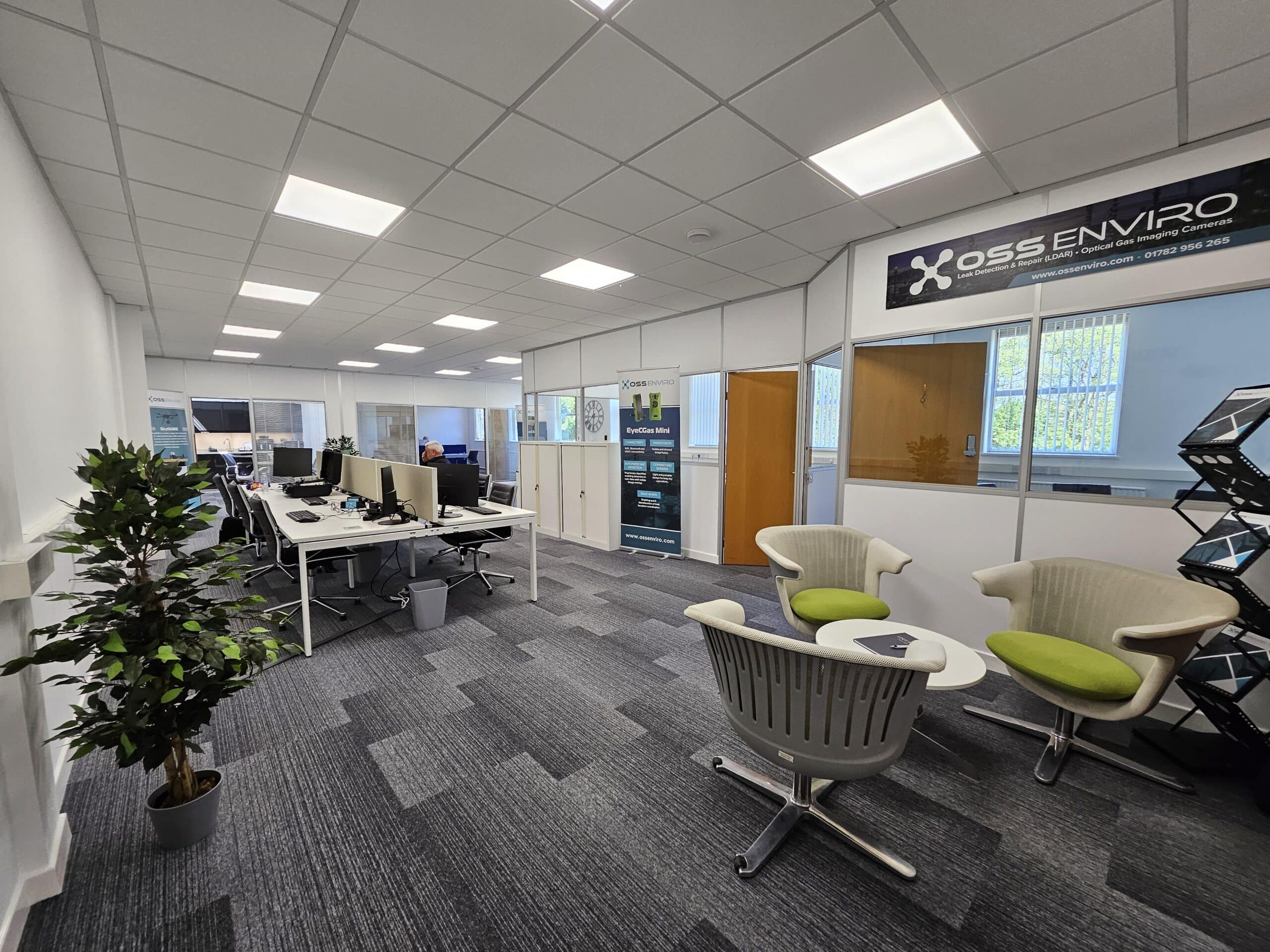 A bright and modern open-plan office at OSS Enviro’s new headquarters in Cold Meece, featuring collaborative desk spaces, a small breakout seating area, and branded signage.