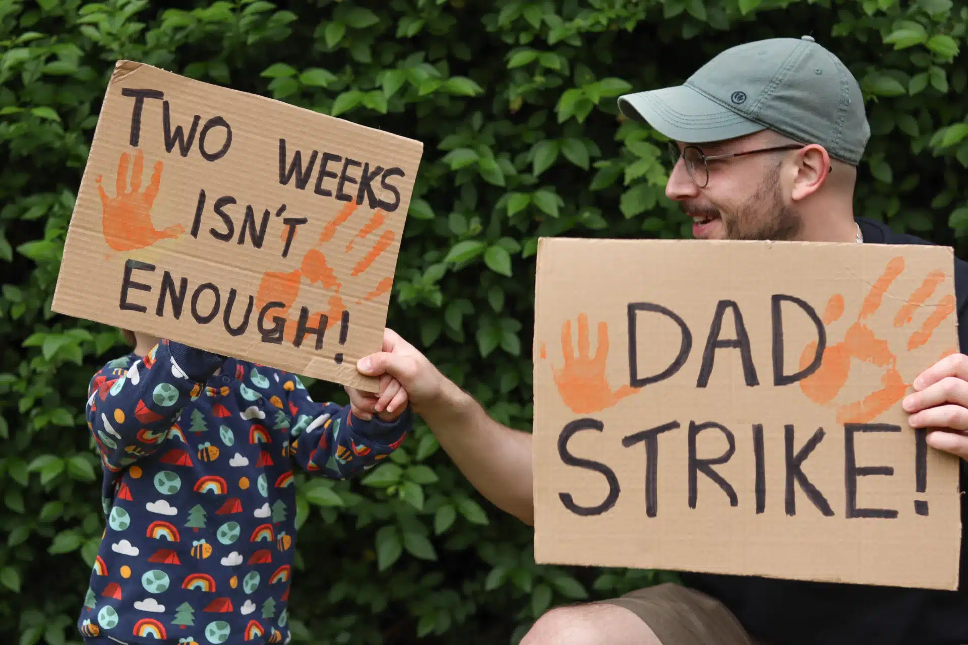 Close-up of campaign materials from the Dad Strike, including printed signs and baby grows highlighting calls for fairer paternity leave.