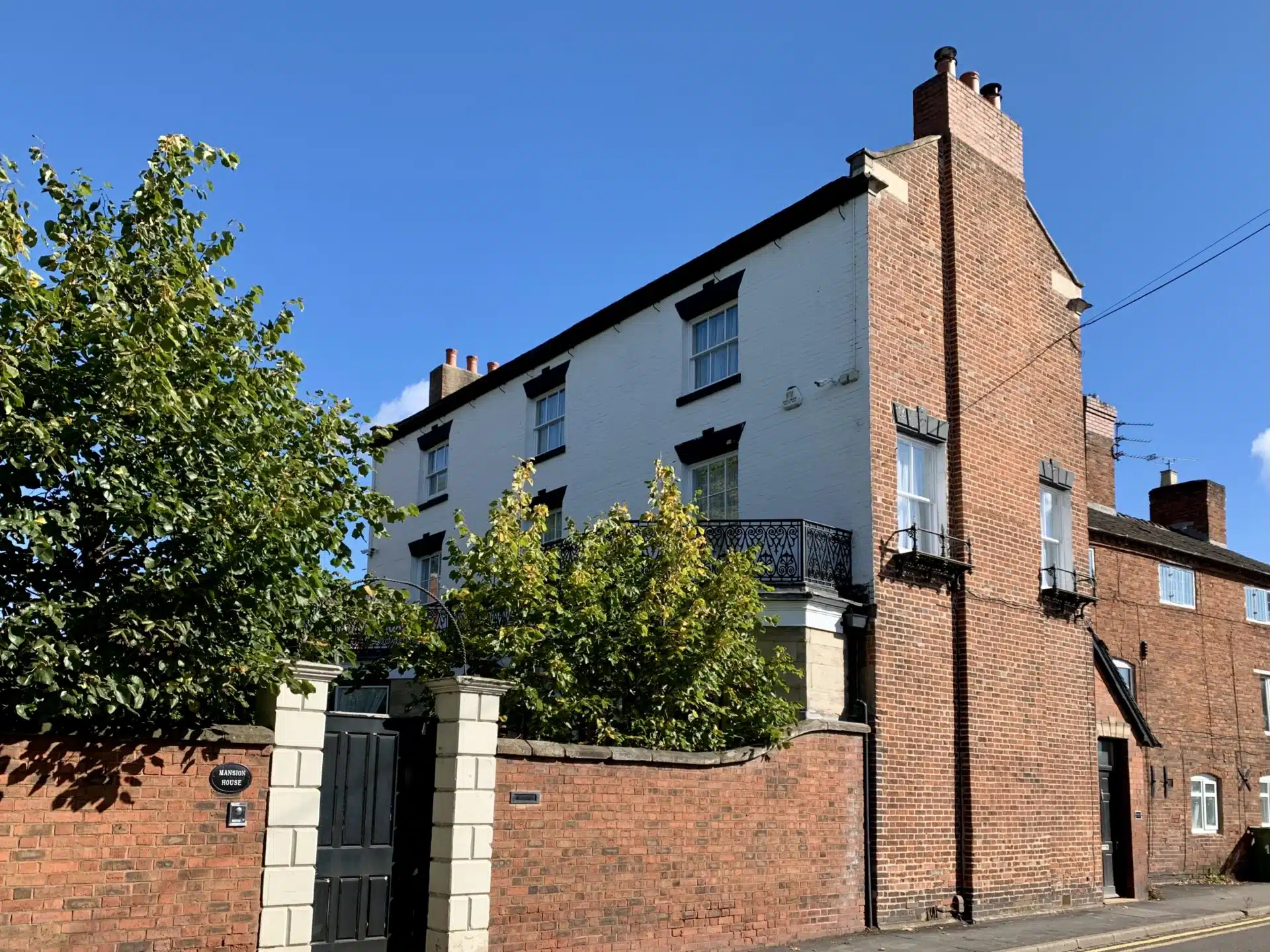 Front view of John Rangeley’s former home on Lichfield Street in Stone, a three-storey red brick Georgian townhouse with arched windows and an ornate black cast iron balcony.