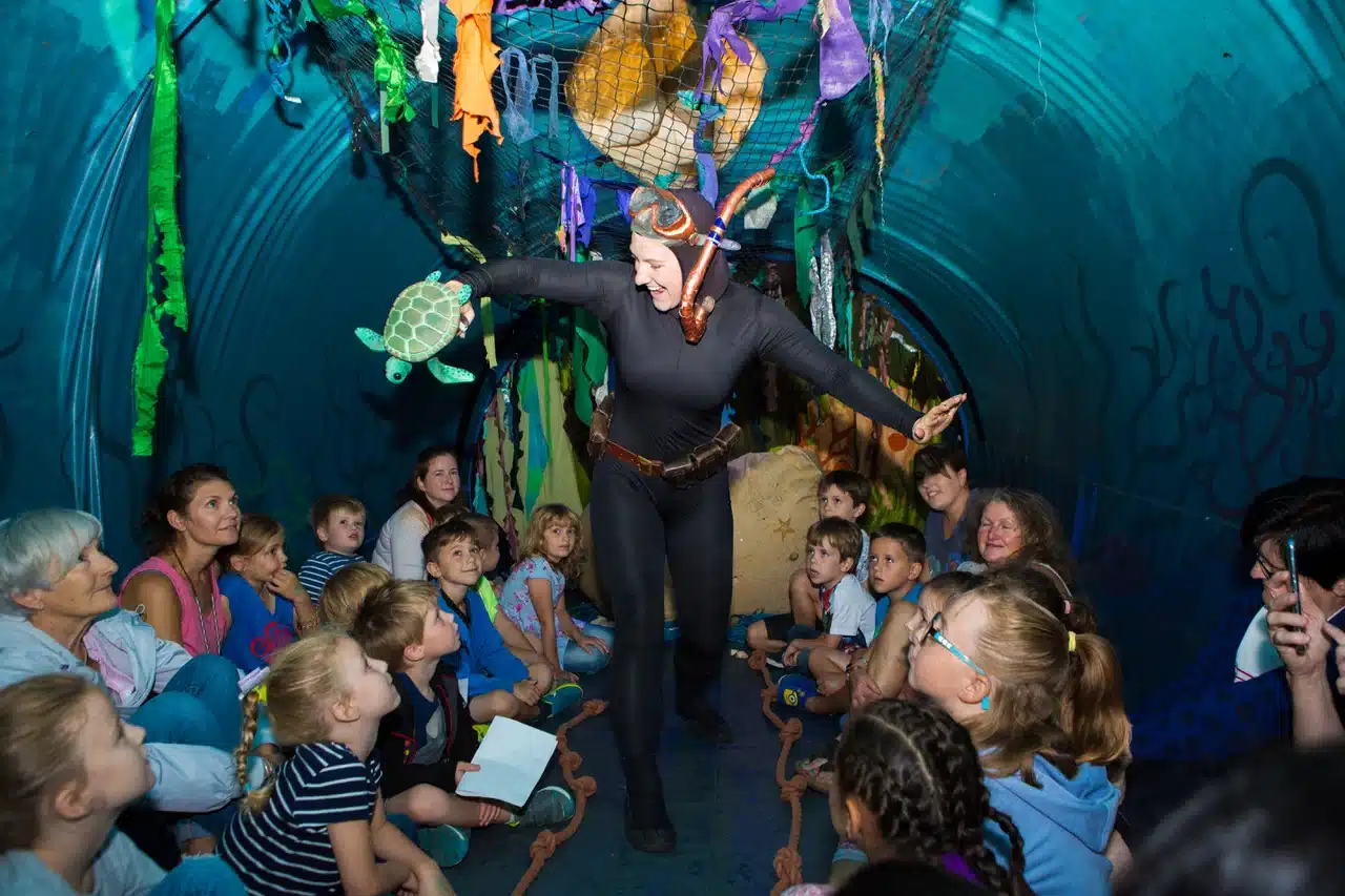 Children exploring the interior of the inflatable whale during an interactive show in a public park.