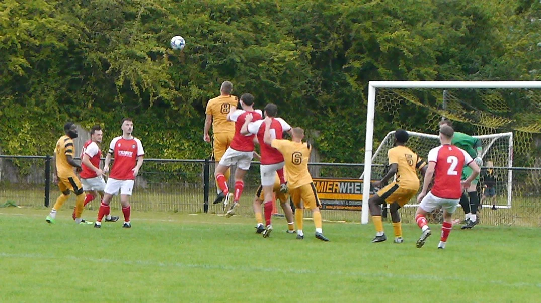 Stone Old Alleynians players crowd the box during a corner, looking to convert their pressure into a goal.