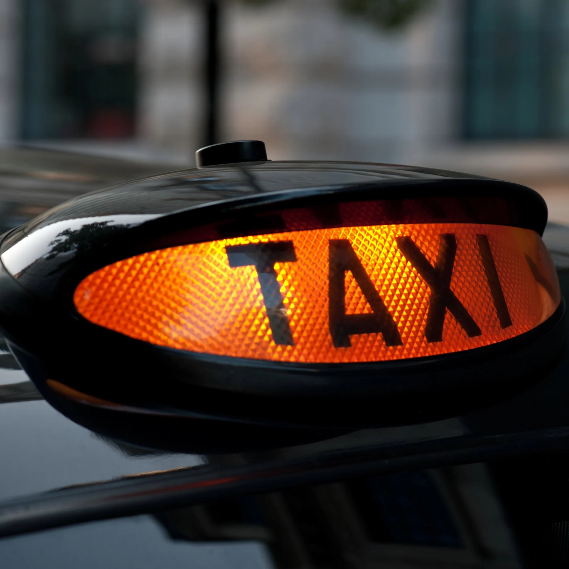 Orange Taxi sign on a black taxi cab