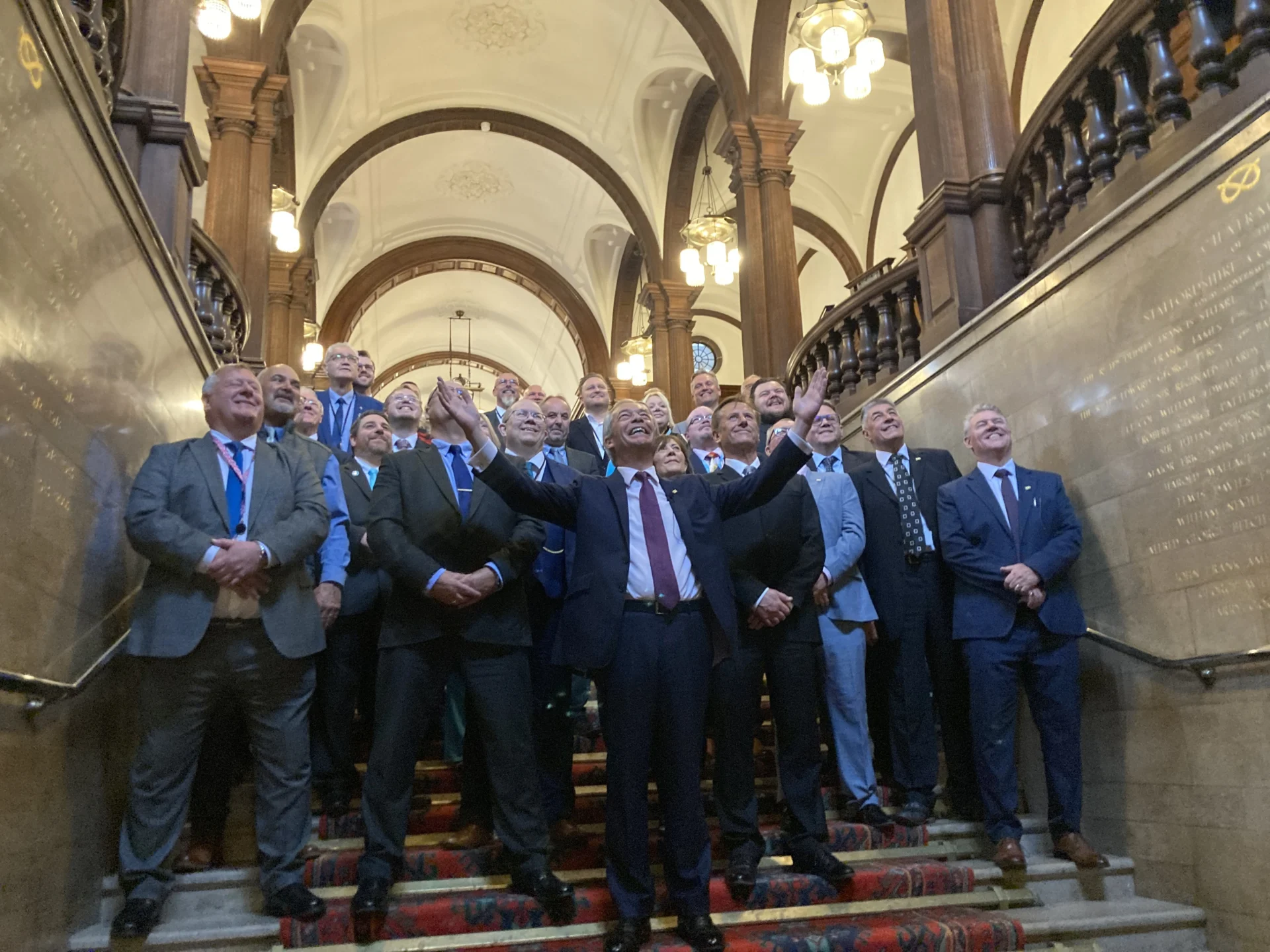 Group of councillors and political representatives standing on a staircase inside a council building.