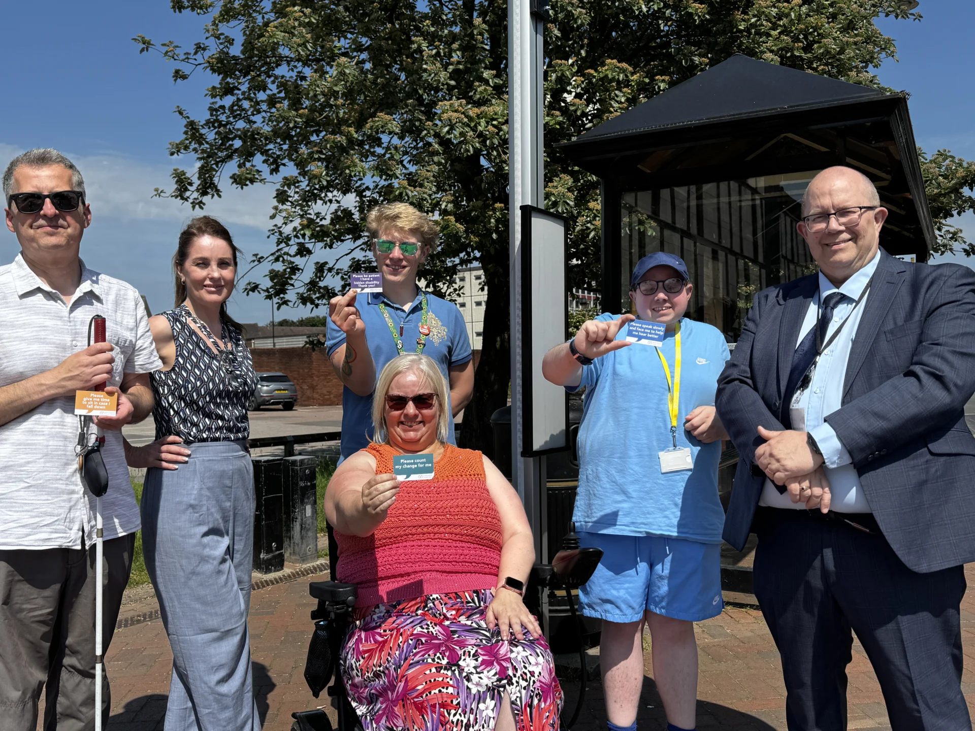 People holding Travel Assistance Cards at a Staffordshire bus stop as part of the Celebrating Differences Inclusive Travel campaign.