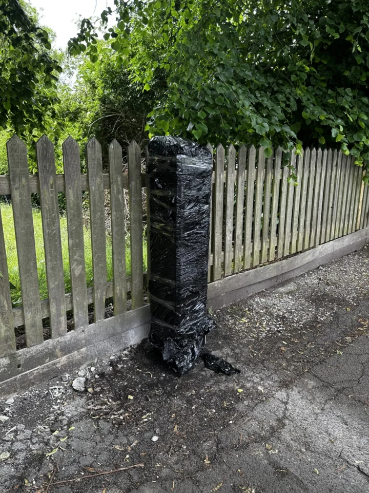 A covered machine beside a wooden fence on Station Approach near Stone railway station.