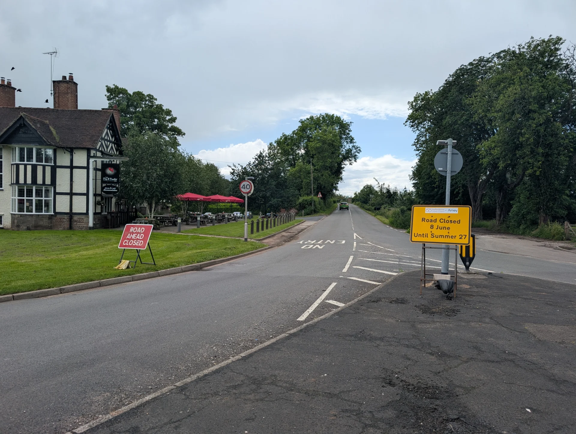Road closure signs on Sandon Road outside The Dog and Doublet Inn, with the B5066 stretching ahead towards Hopton.
