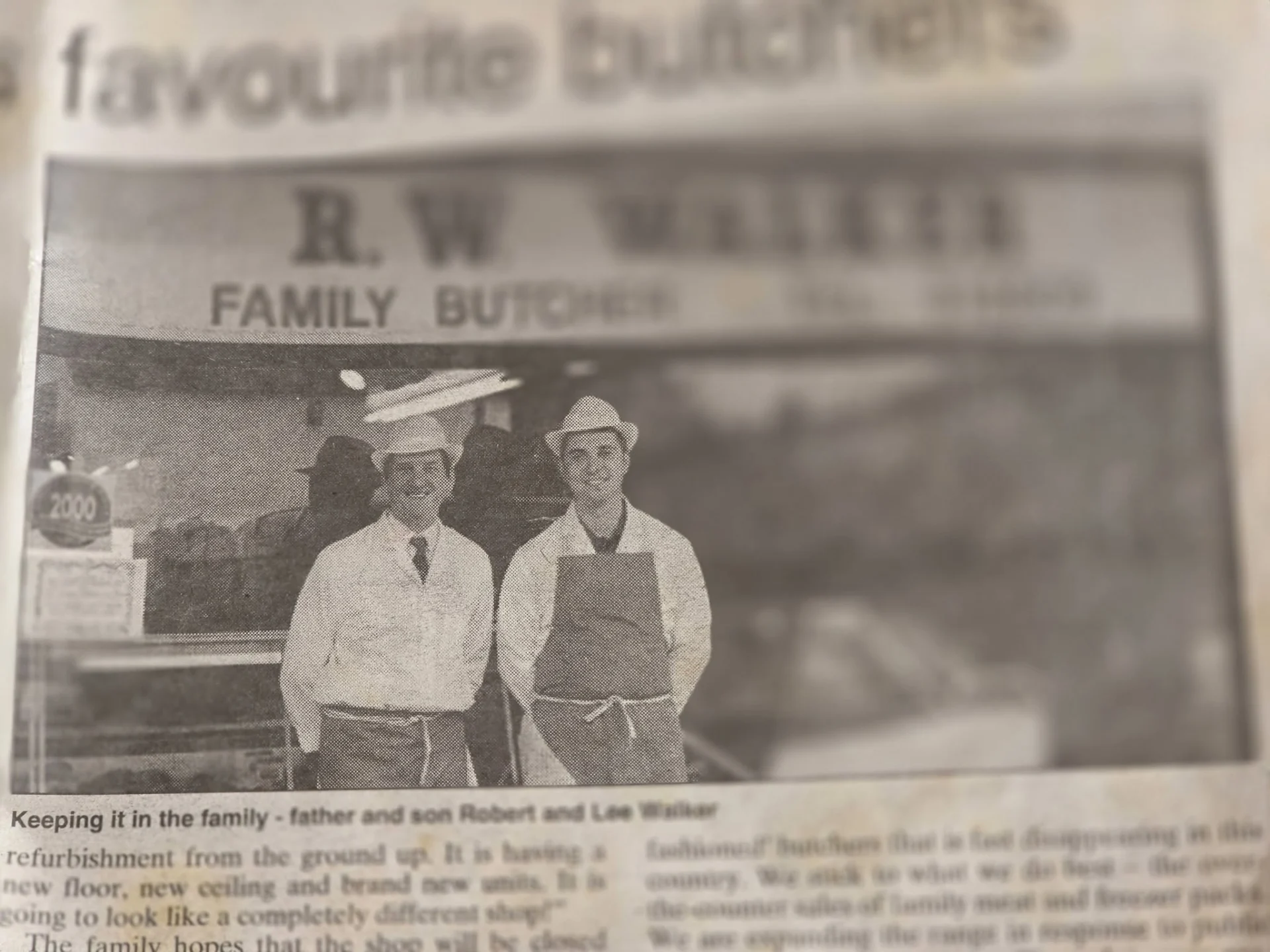 Archive newspaper photograph showing two butchers outside the former R W Walker Family Butcher shop.