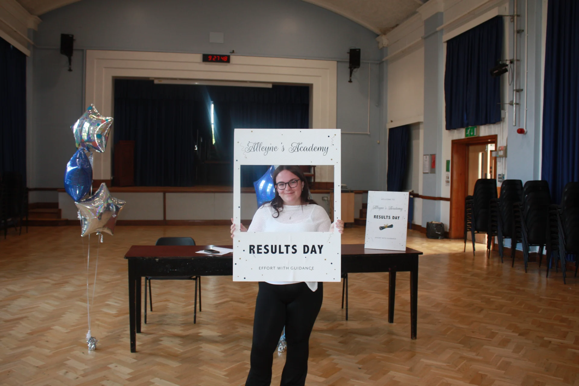 An Alleyne’s Academy student holding a Results Day photo frame in the school hall in Stone.