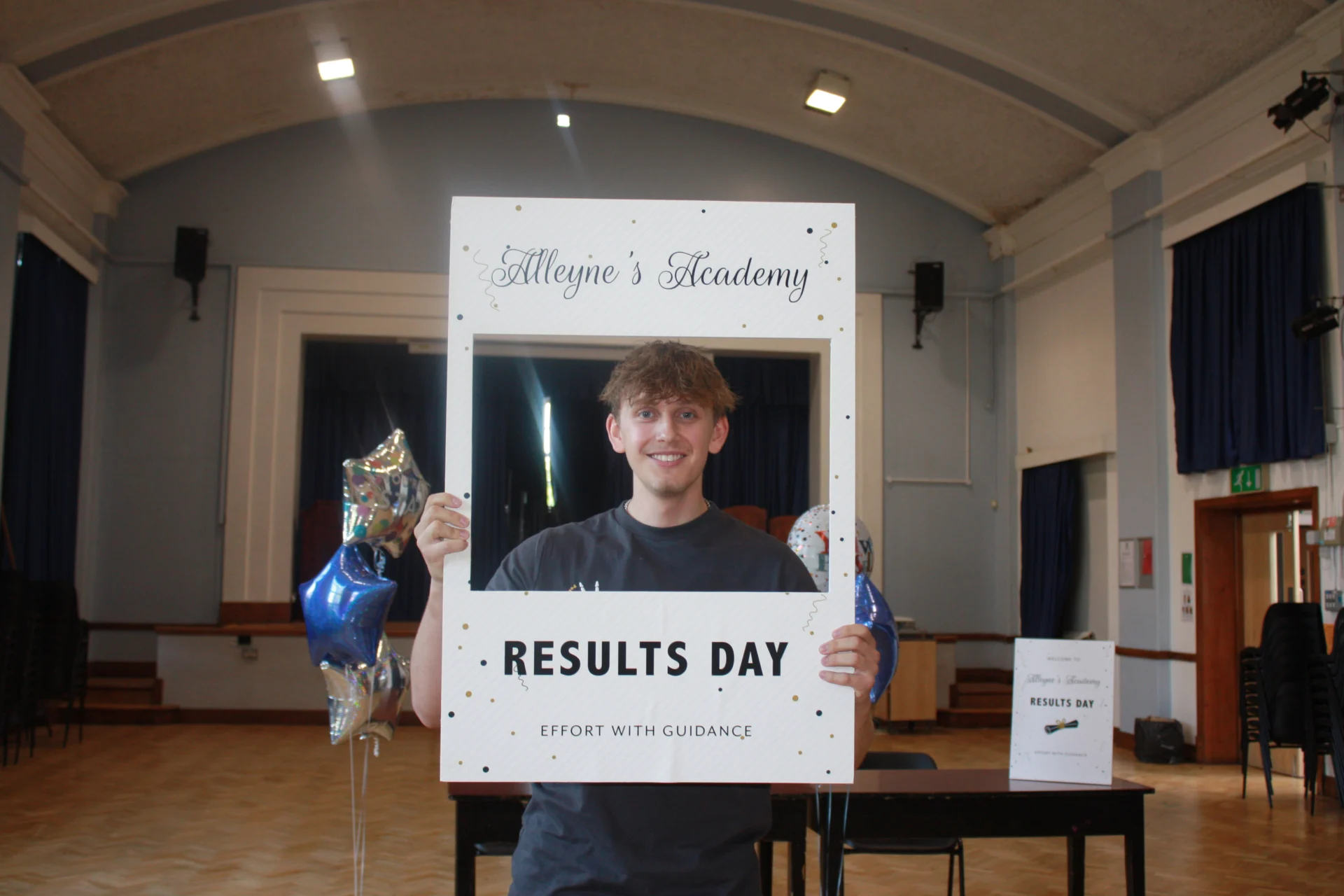 An Alleyne’s Academy student holding a Results Day photo frame in the school hall in Stone.
