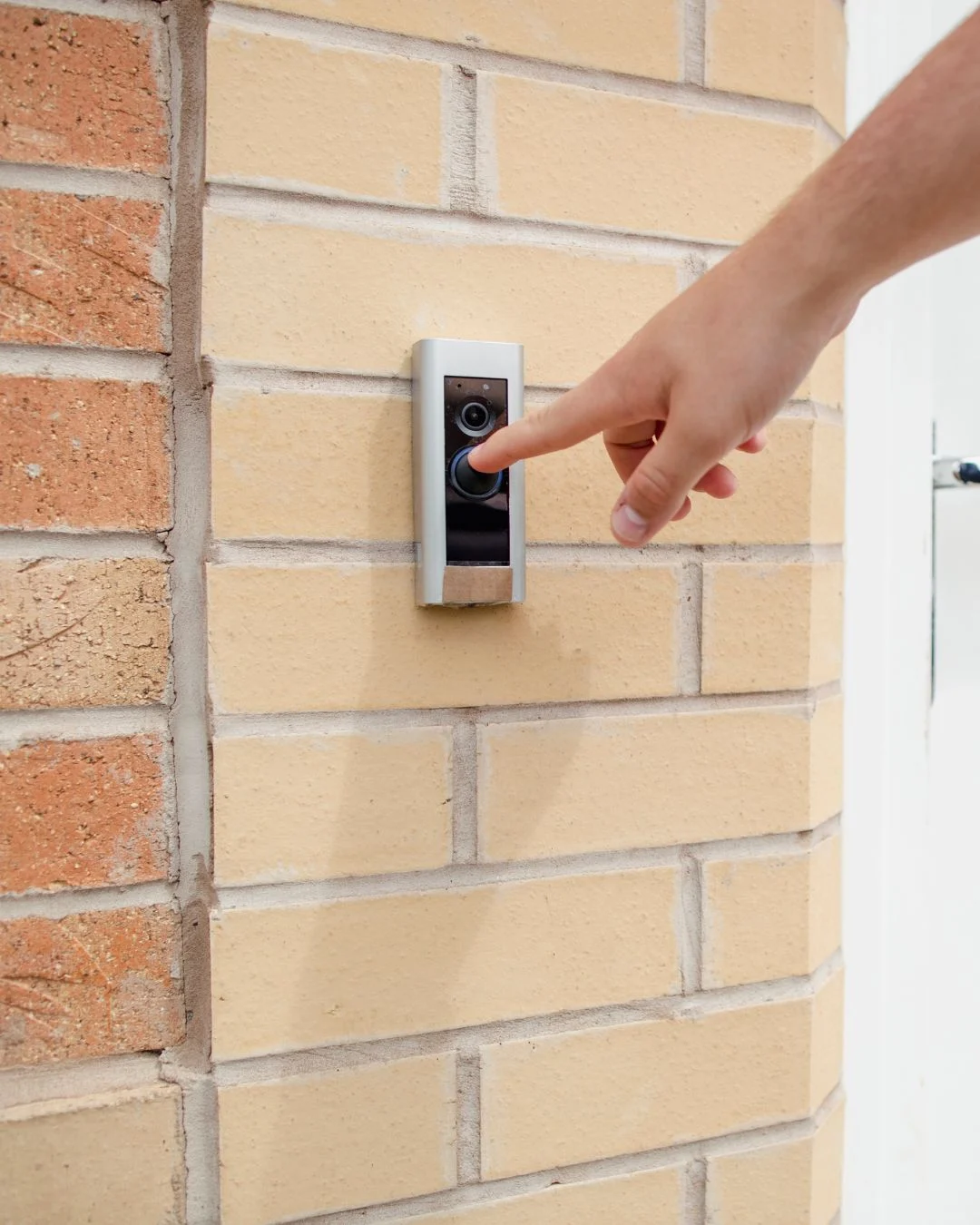 Person pushes a video doorbell on the outside of a property.