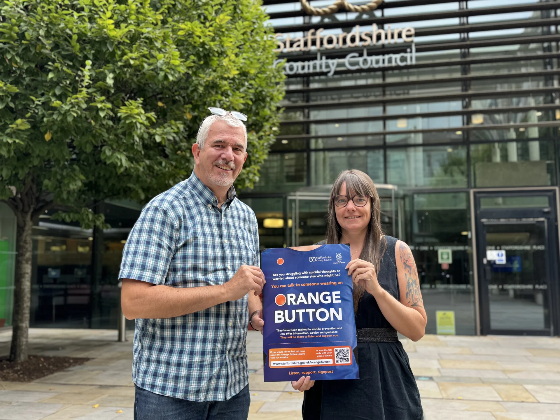 Chris Stanley and Sarah Tunnicliffe outside SP1 with Orange Button poster