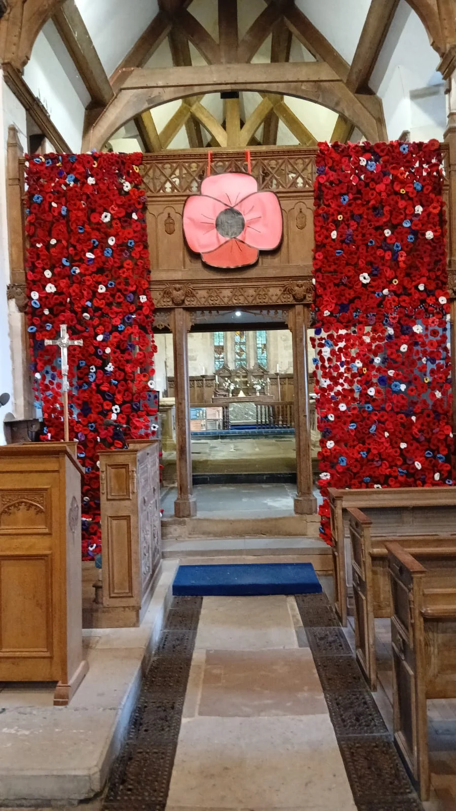 Two large panels of red handmade poppies surrounding the entrance to the chancel inside All Saints’ Church, Sandon, with a large pink poppy above.